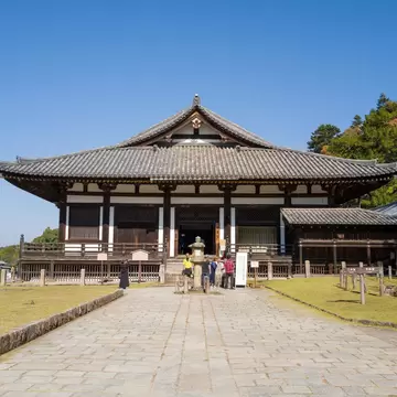 **RIGHTS MANAGED** Uploaded for use on the LP APP

Nara, Japan - November 3, 2023: The image shows the front view of Todai-ji Hokkedo main hall with traditional Japanese architecture, tiled roof, and groups of visitors standing on the stone path under a clear blue sky.