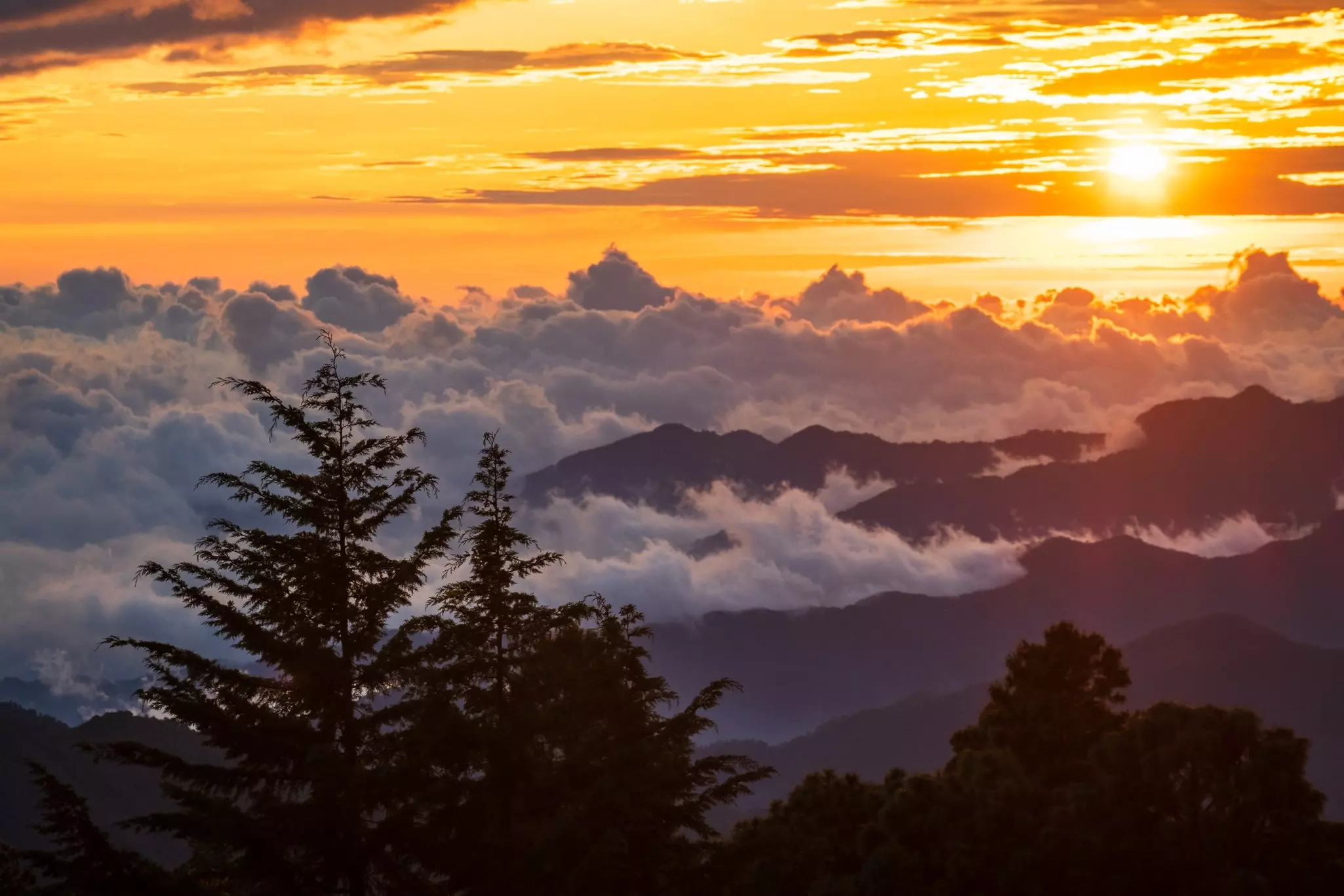 Clouds hugging a mountain landscape at sunset.