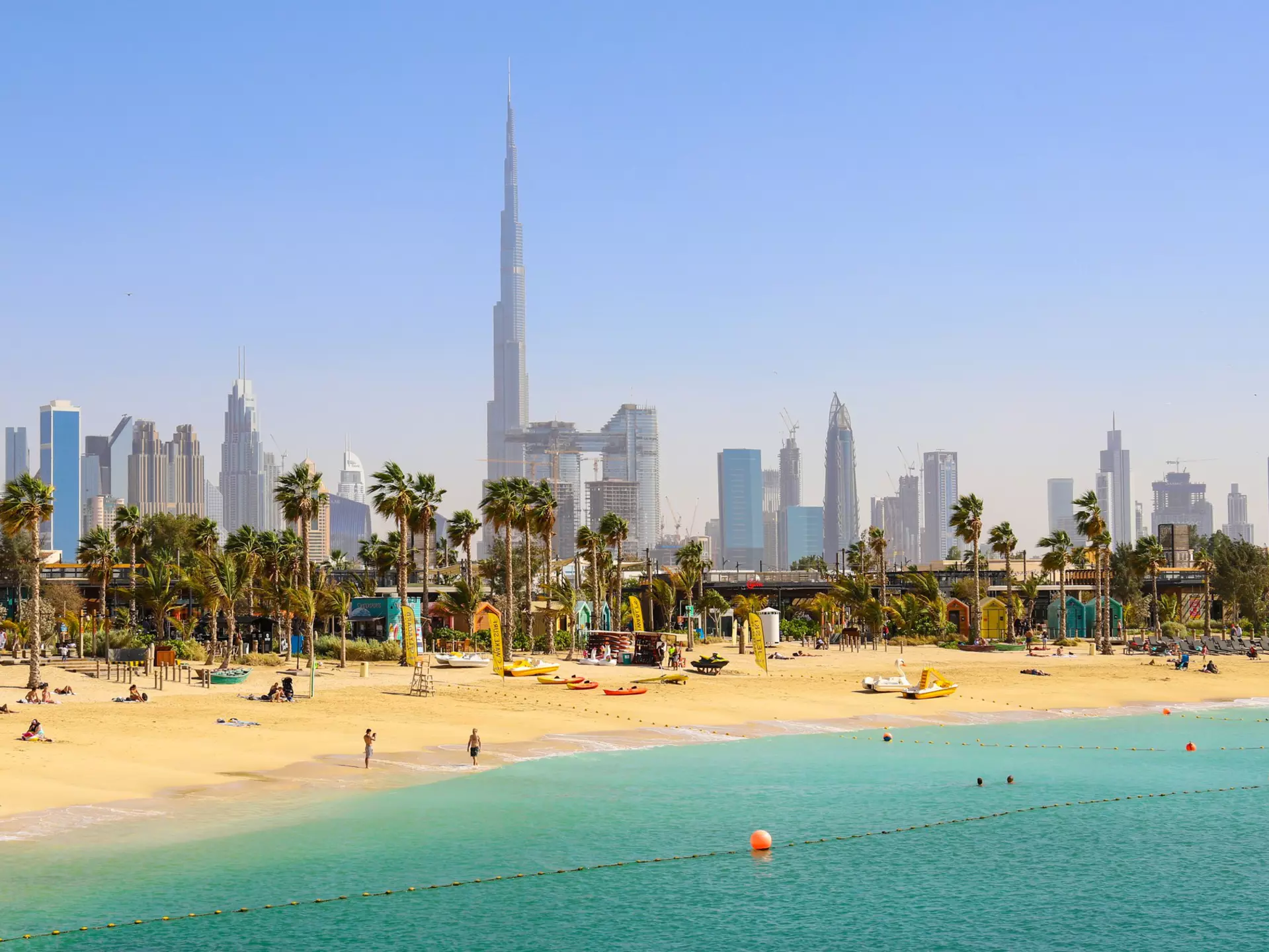 People at La Mer Beach with skyscrapers of Dubai in the background