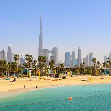 People at La Mer Beach with skyscrapers of Dubai in the background