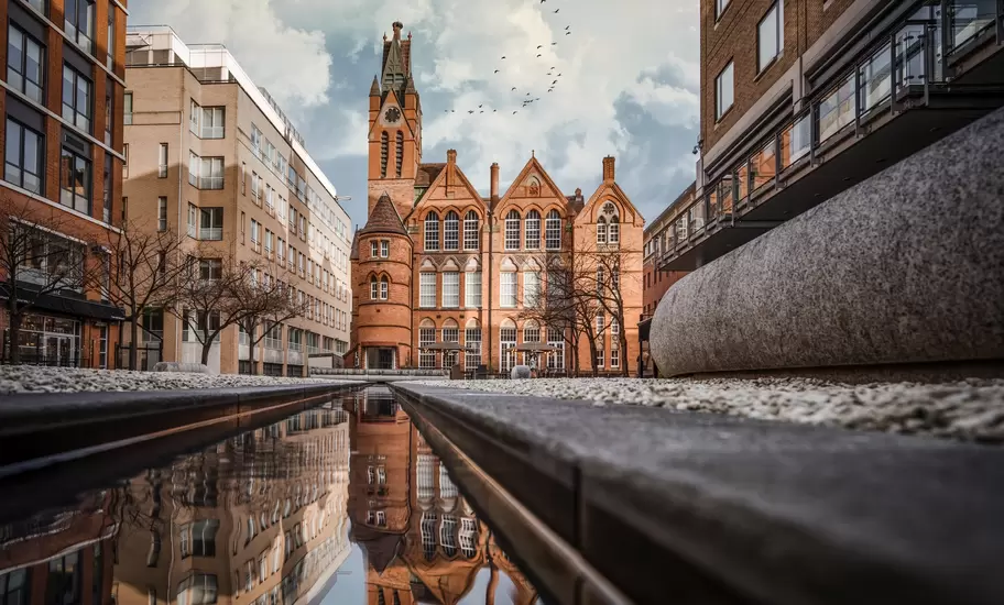 Birmingham: the red-brick Gothic Ikon Gallery reflected in a narrow water channel between modern apartment blocks