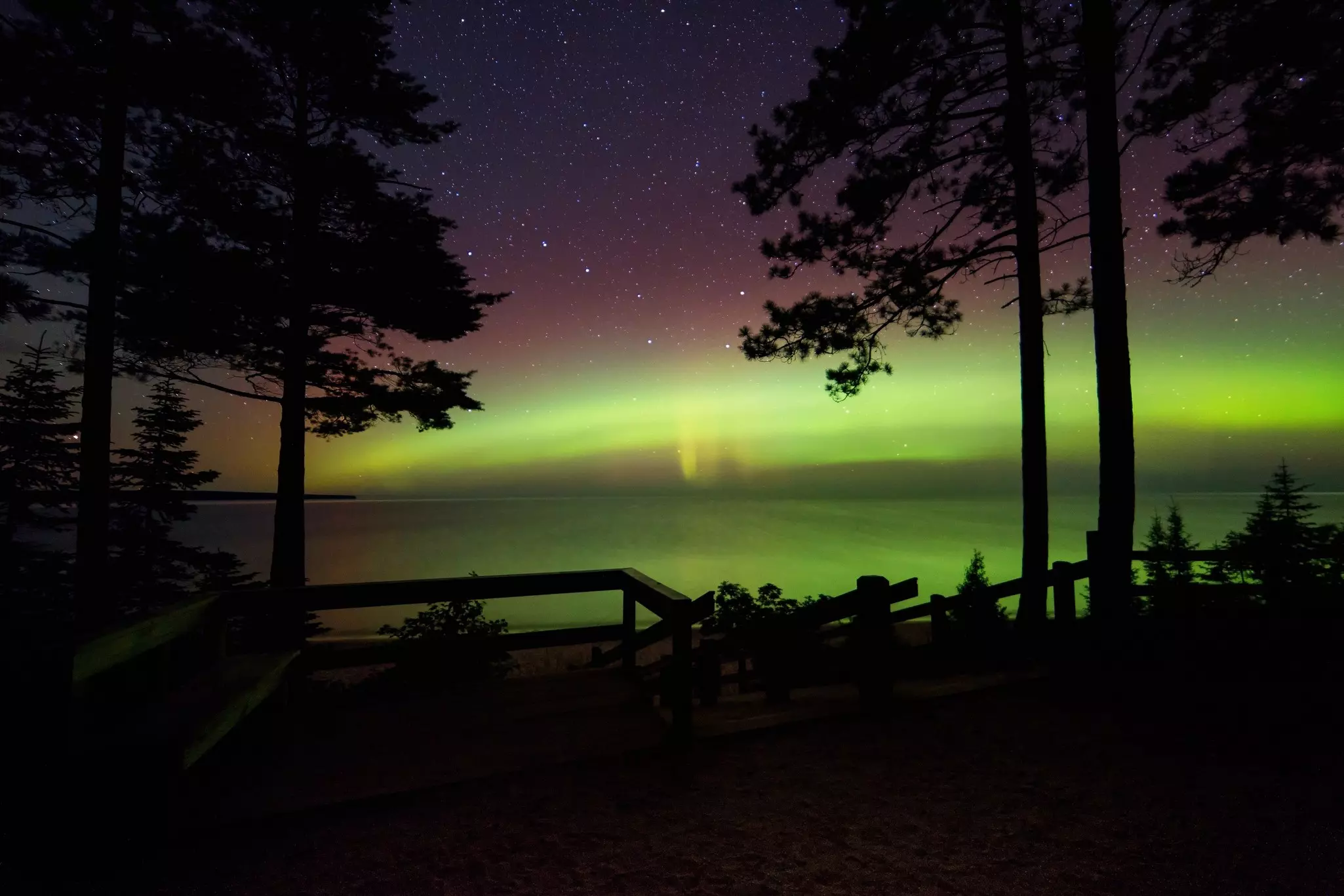 The Big Dipper over a lake with the northern lights along the horizon.