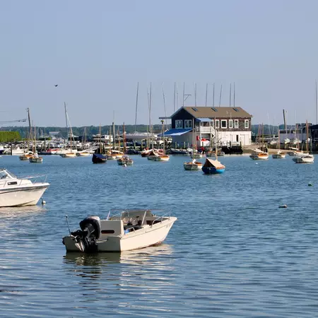 Looking across the water at several boats that are docked at the marina.