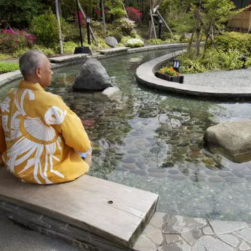 Elderly couple in kimonos dipping feet in ornamental foot bath, Oedo Onsen Monotogari, Odaiba.
