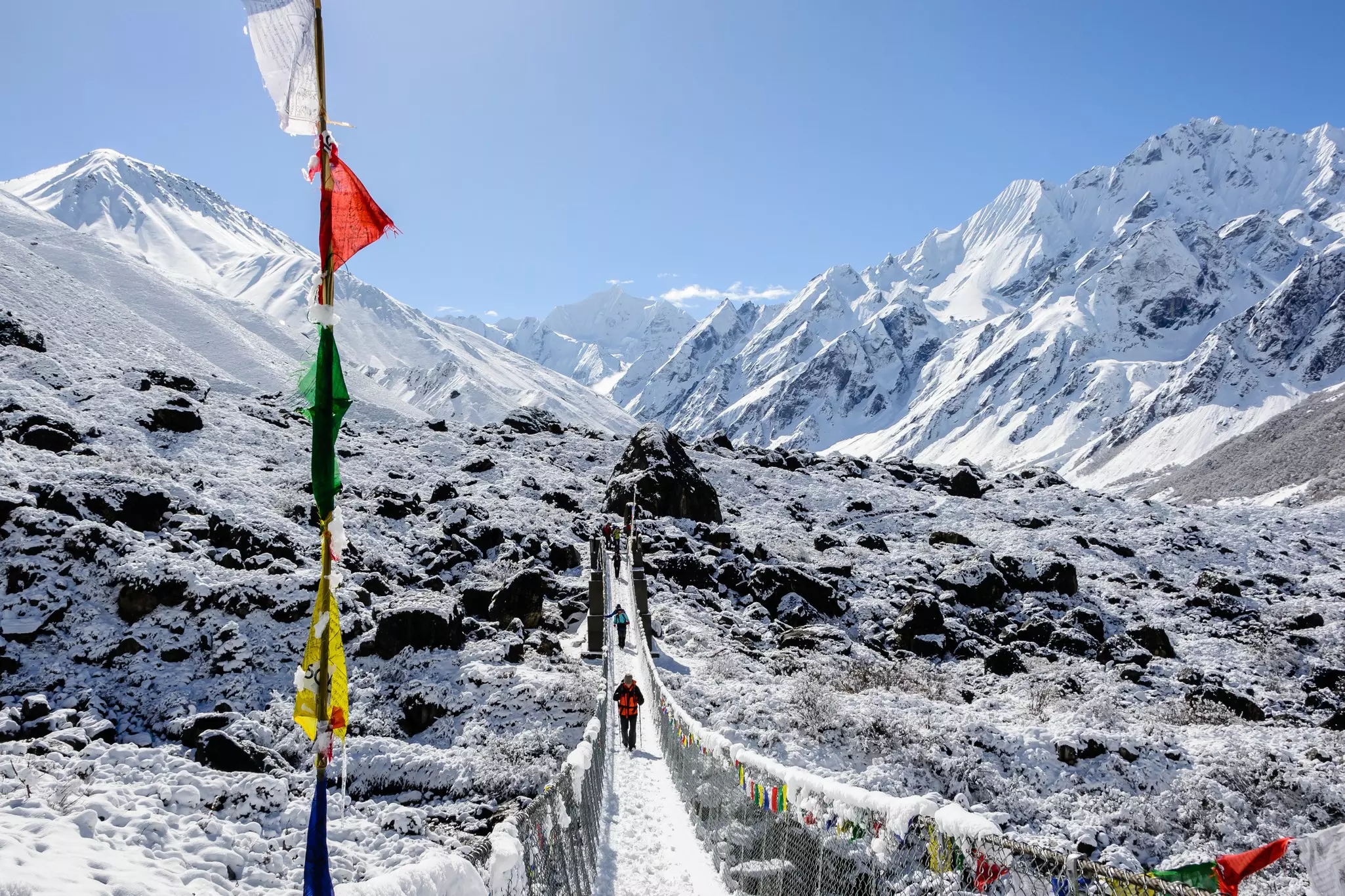 People walking on a pedestrian bridge over a snowy landscape