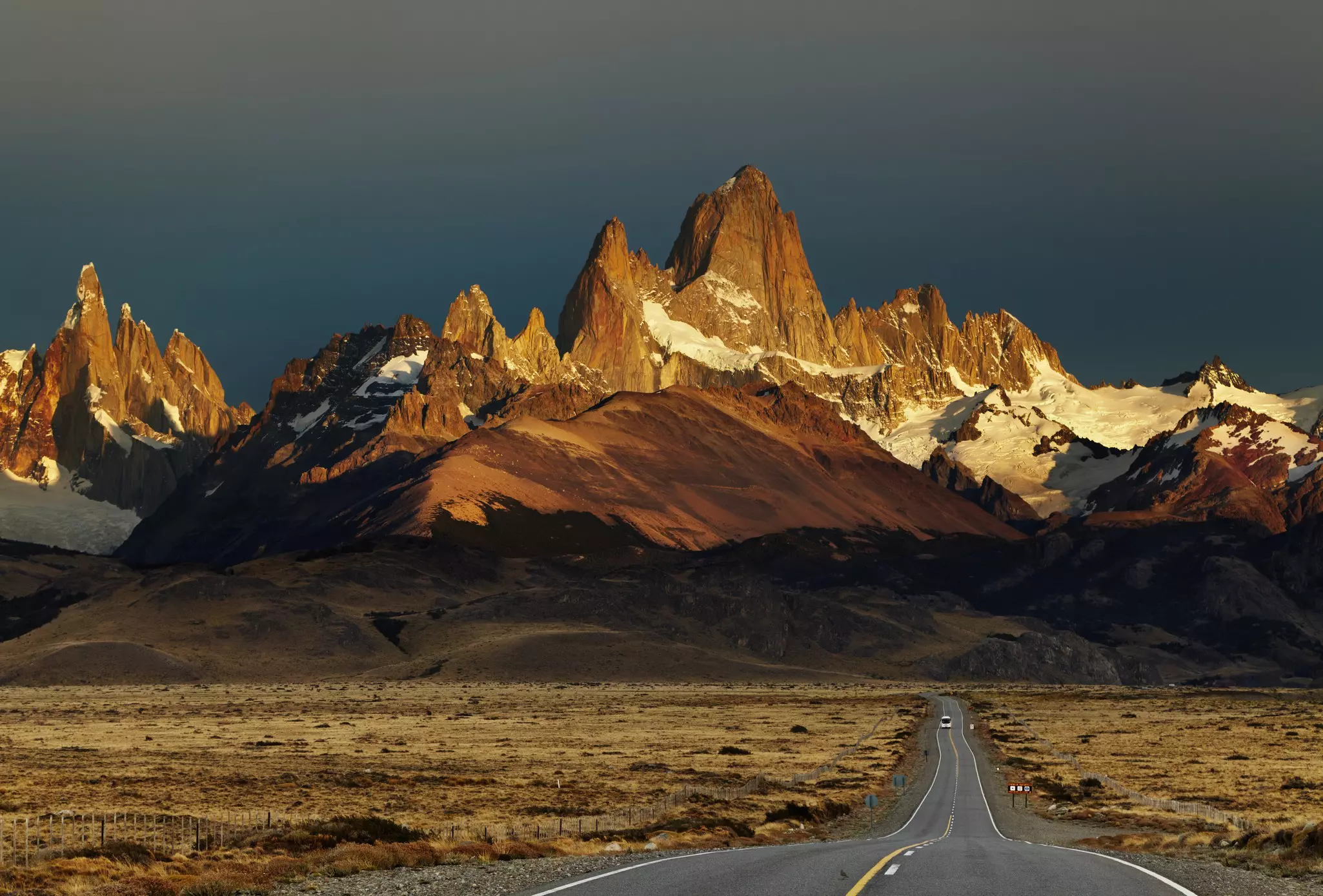 Empty road leading to very pointy mountain peaks
