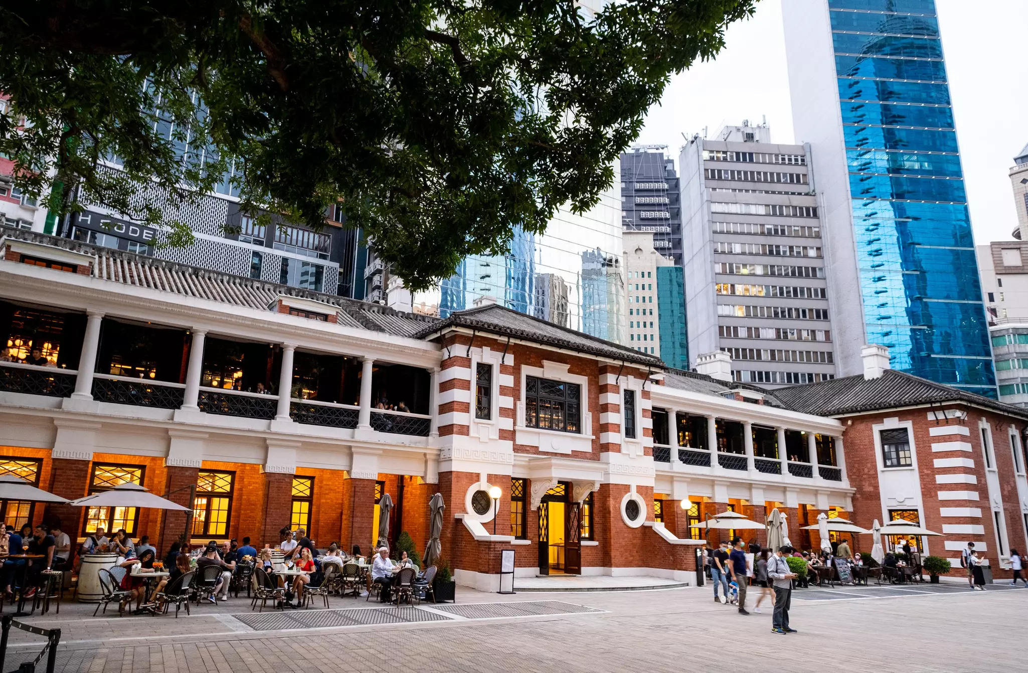 Image of long brick building with tall city skyscrapers in the background.