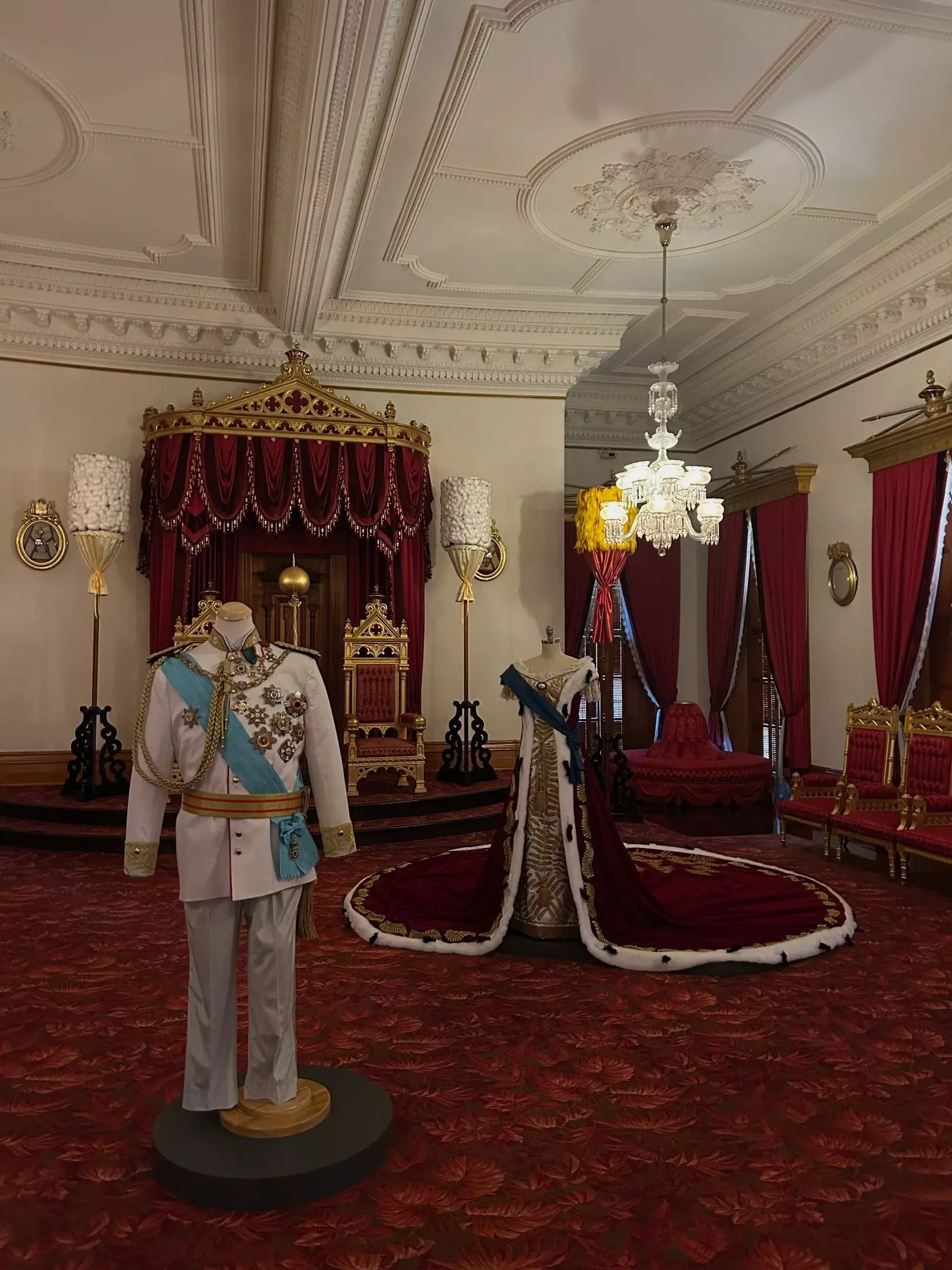 A grand room with royal clothing on display and a throne