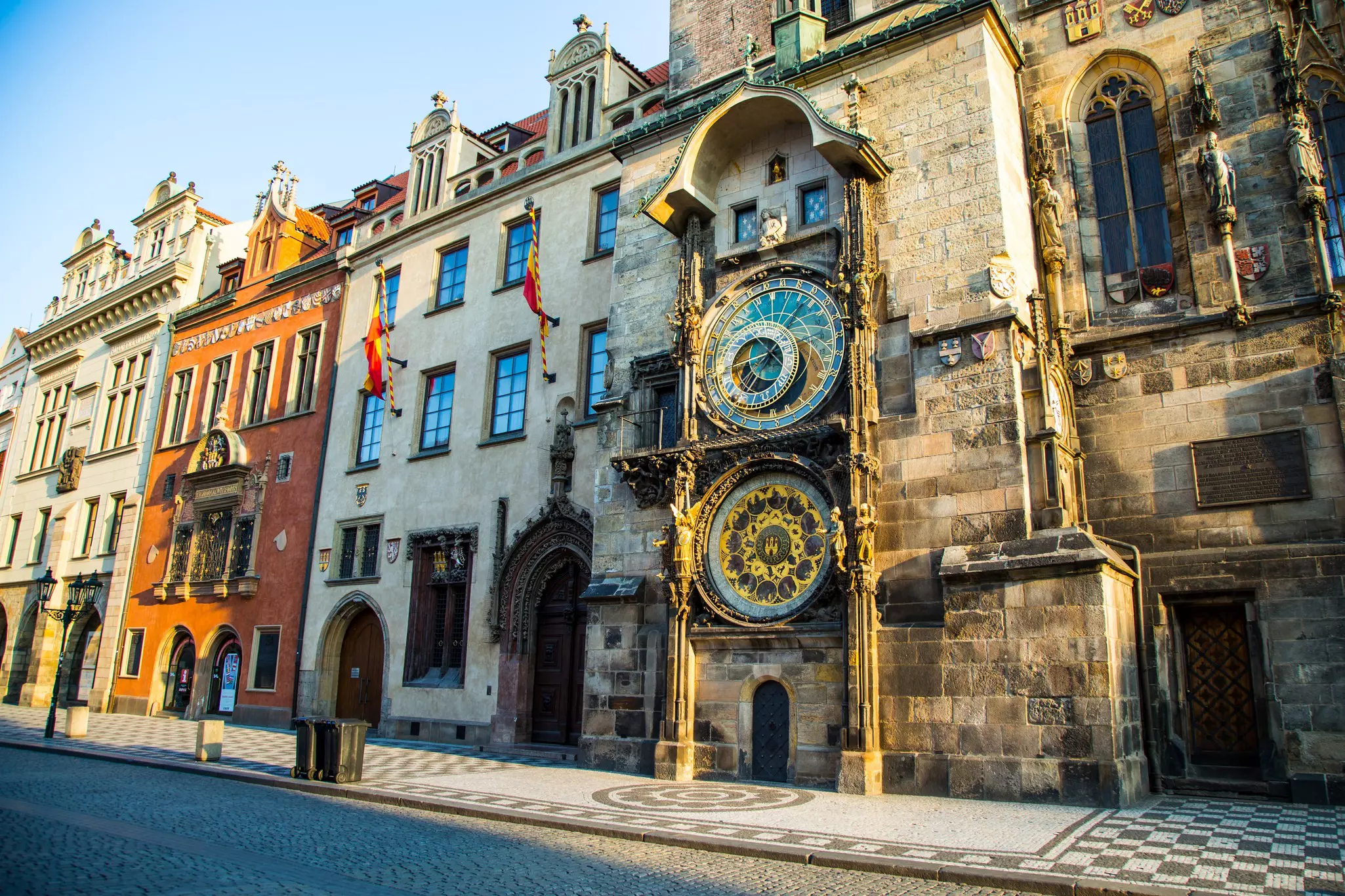 A large astronomical clock with several faces covers the side of a three-story building