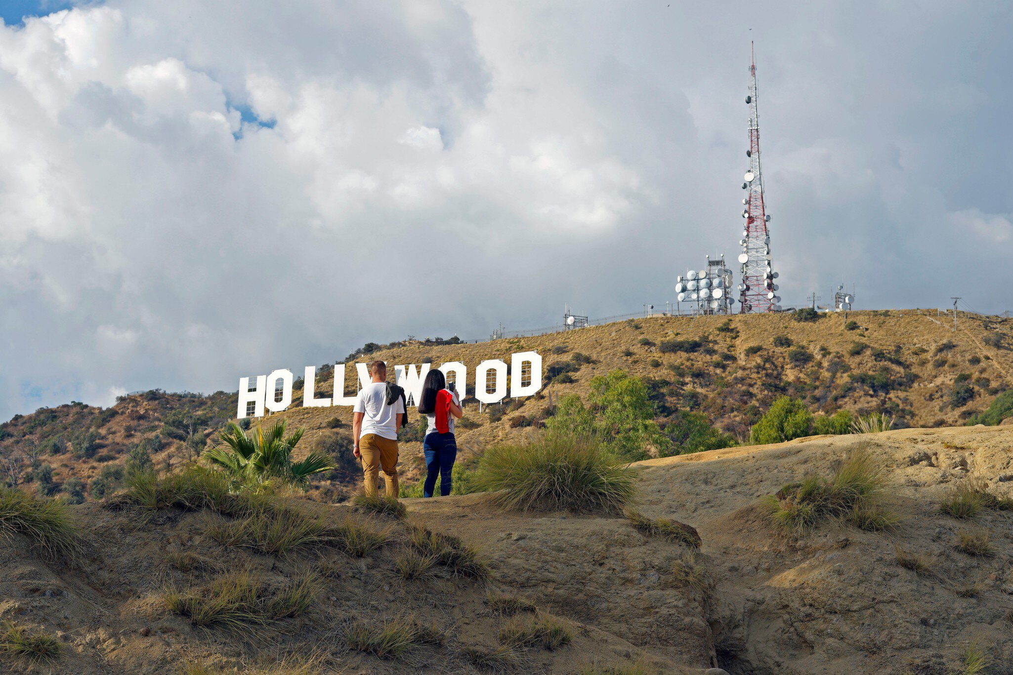 Two hikers in Griffith Park admiring the Hollywood sign in the hills of Los Angeles, California