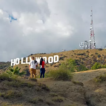 Two hikers in Griffith Park admiring the Hollywood sign in the hills of Los Angeles, California