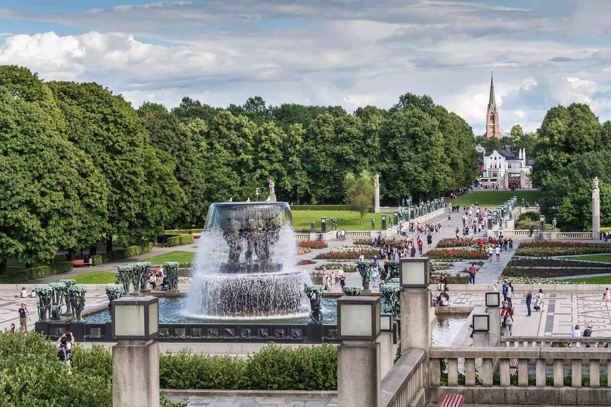 Vigeland sculpture arrangement in Frogner Park, with trees and pedestrians all around