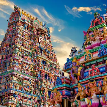 The tall towers of a temple are covered in elaborate multicolored sculptures.