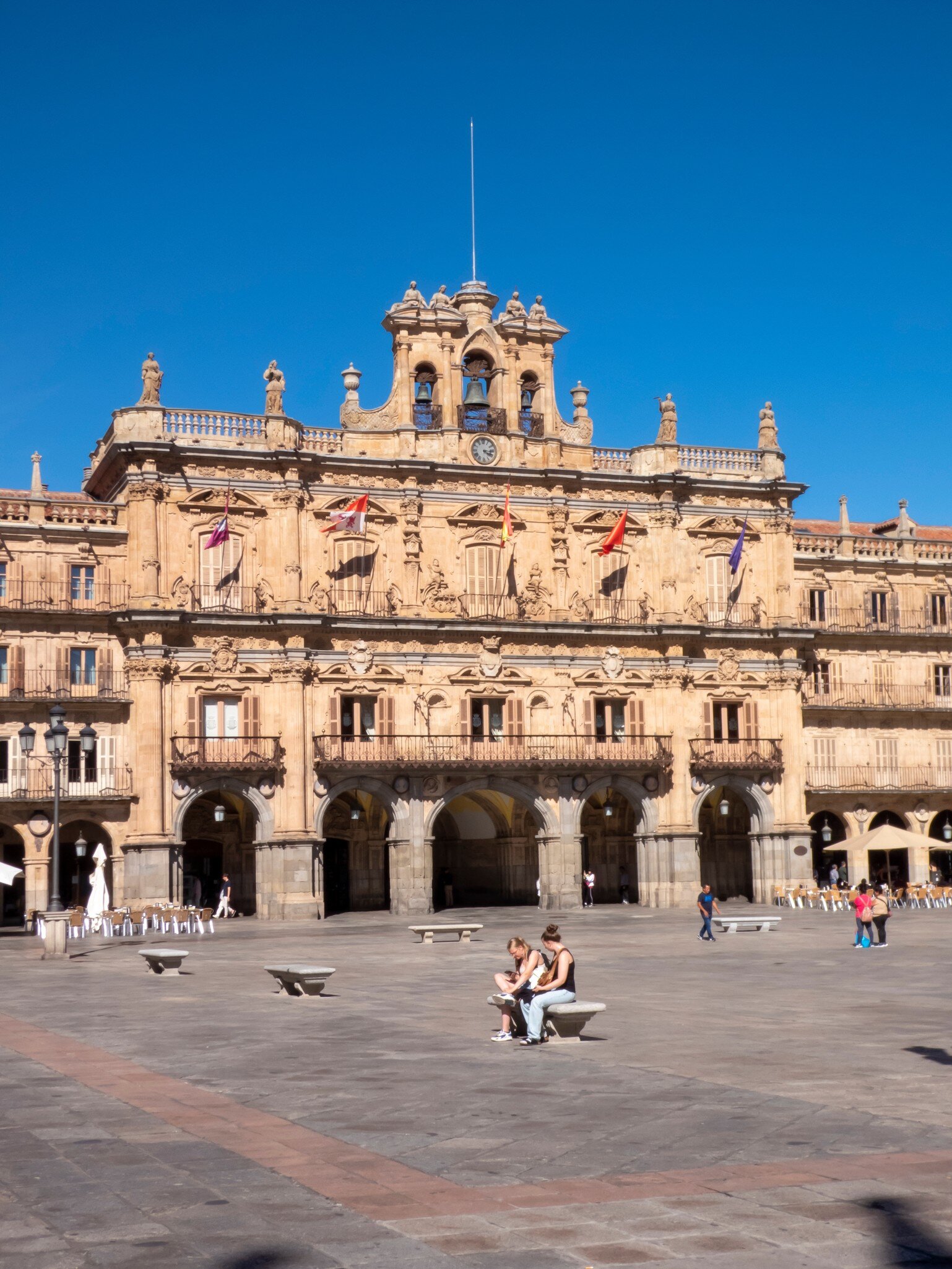 People sitting on Plaza Mayor in Salamanca, Spain, on a sunny day.
