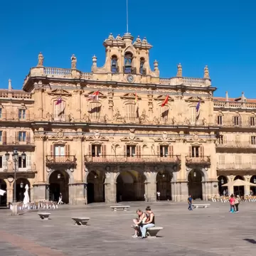 People sitting on Plaza Mayor in Salamanca, Spain, on a sunny day.