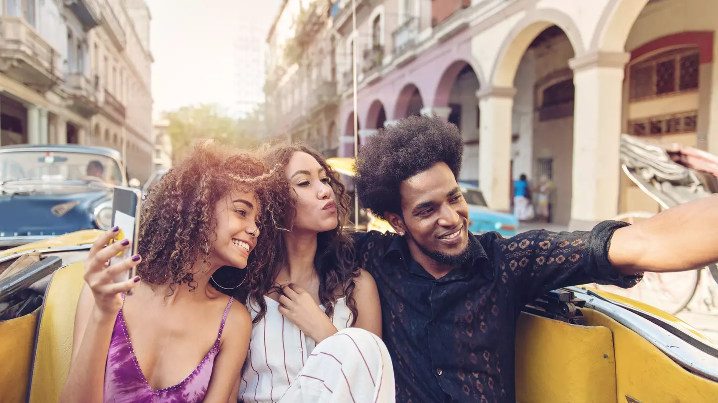 Three friends touring Havana in an old car