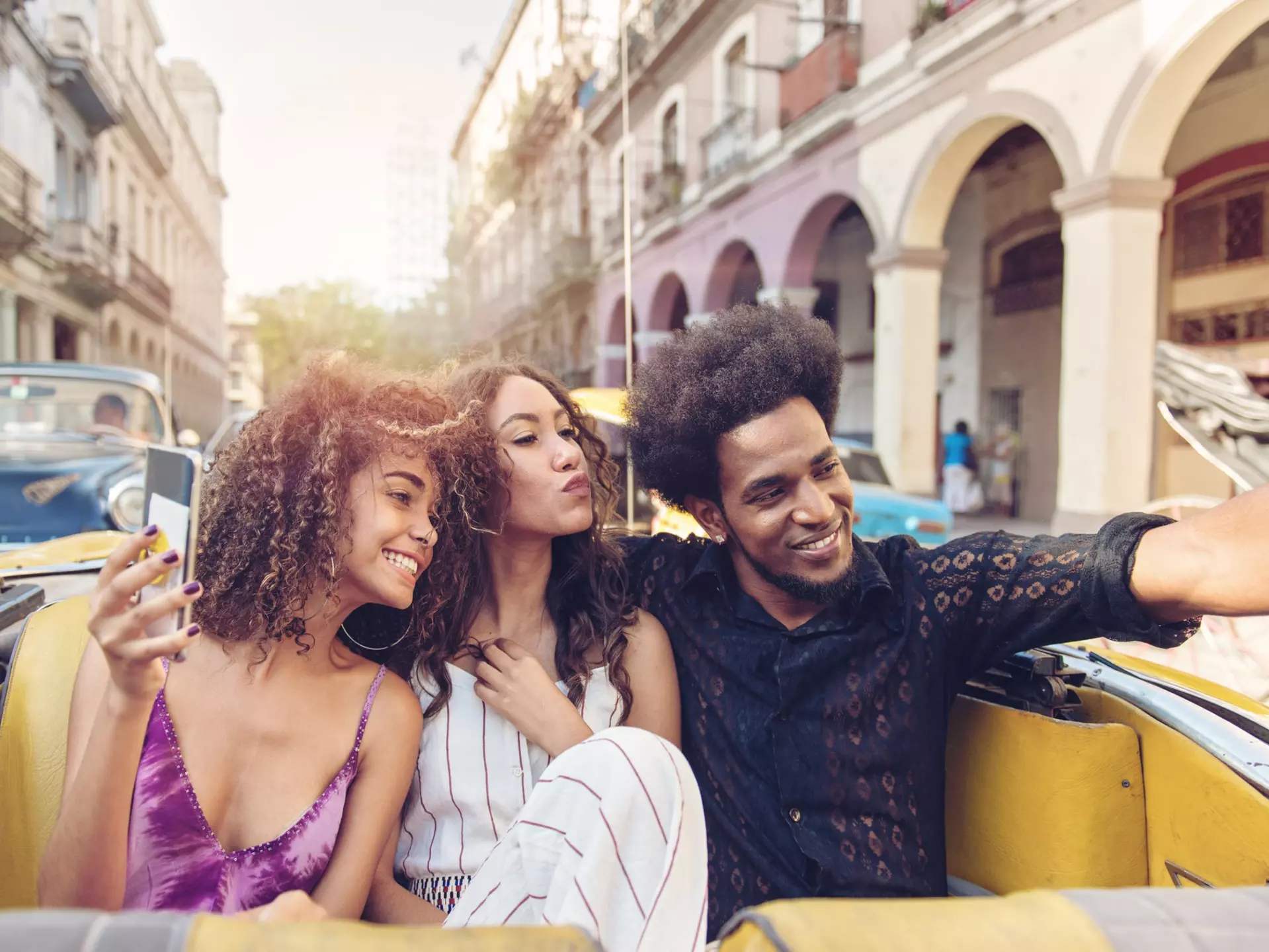 Three friends touring Havana in an old car