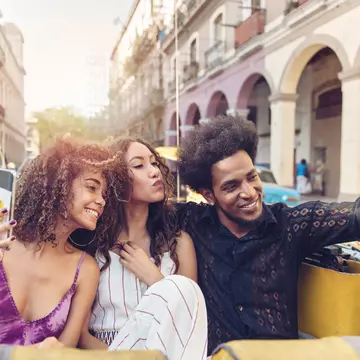 Three friends touring Havana in an old car