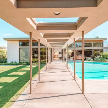 A covered walkway leads to a pool and a mid-century modern home.