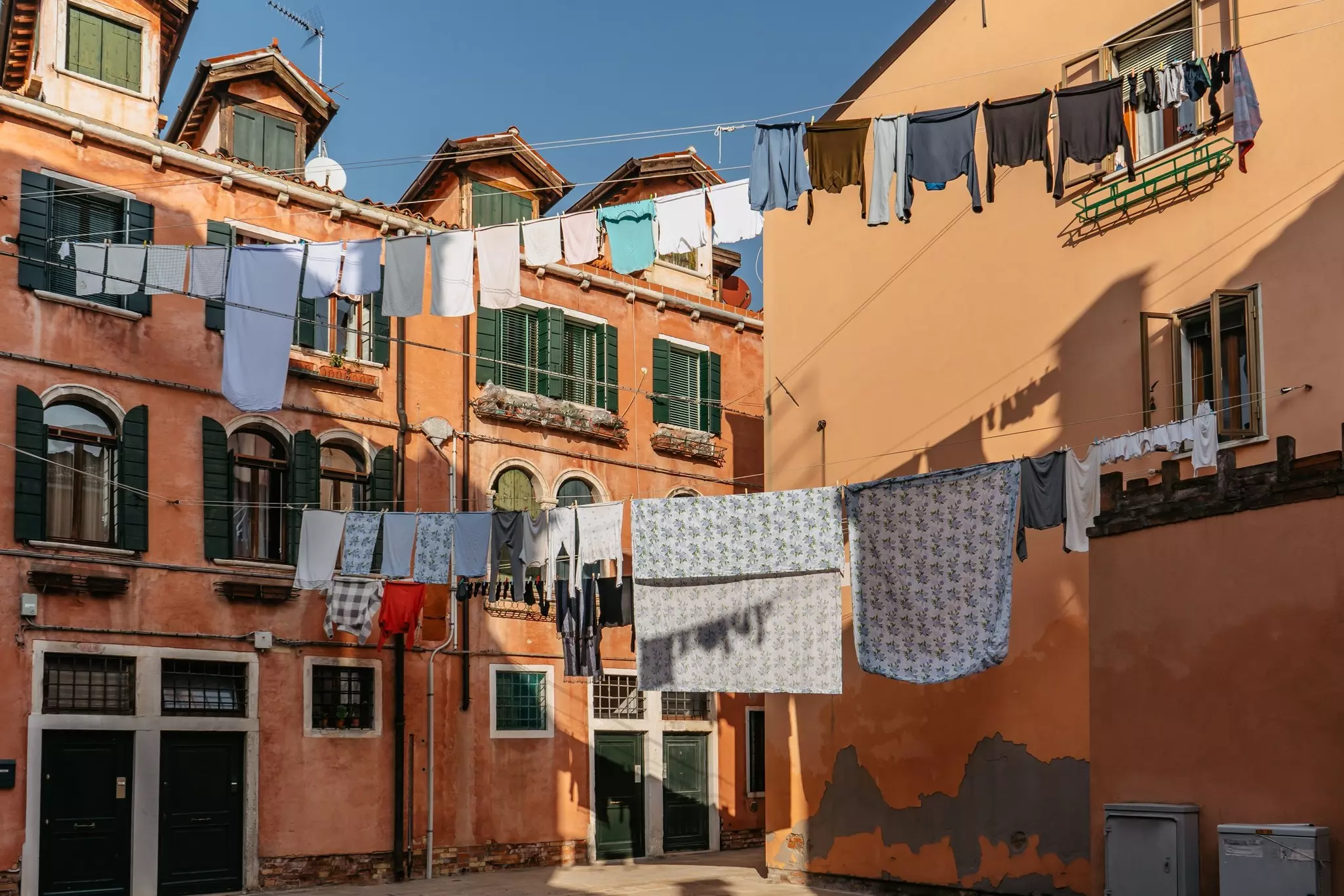 A series of washing lines hanging outside high above the street in a residential part of a town.