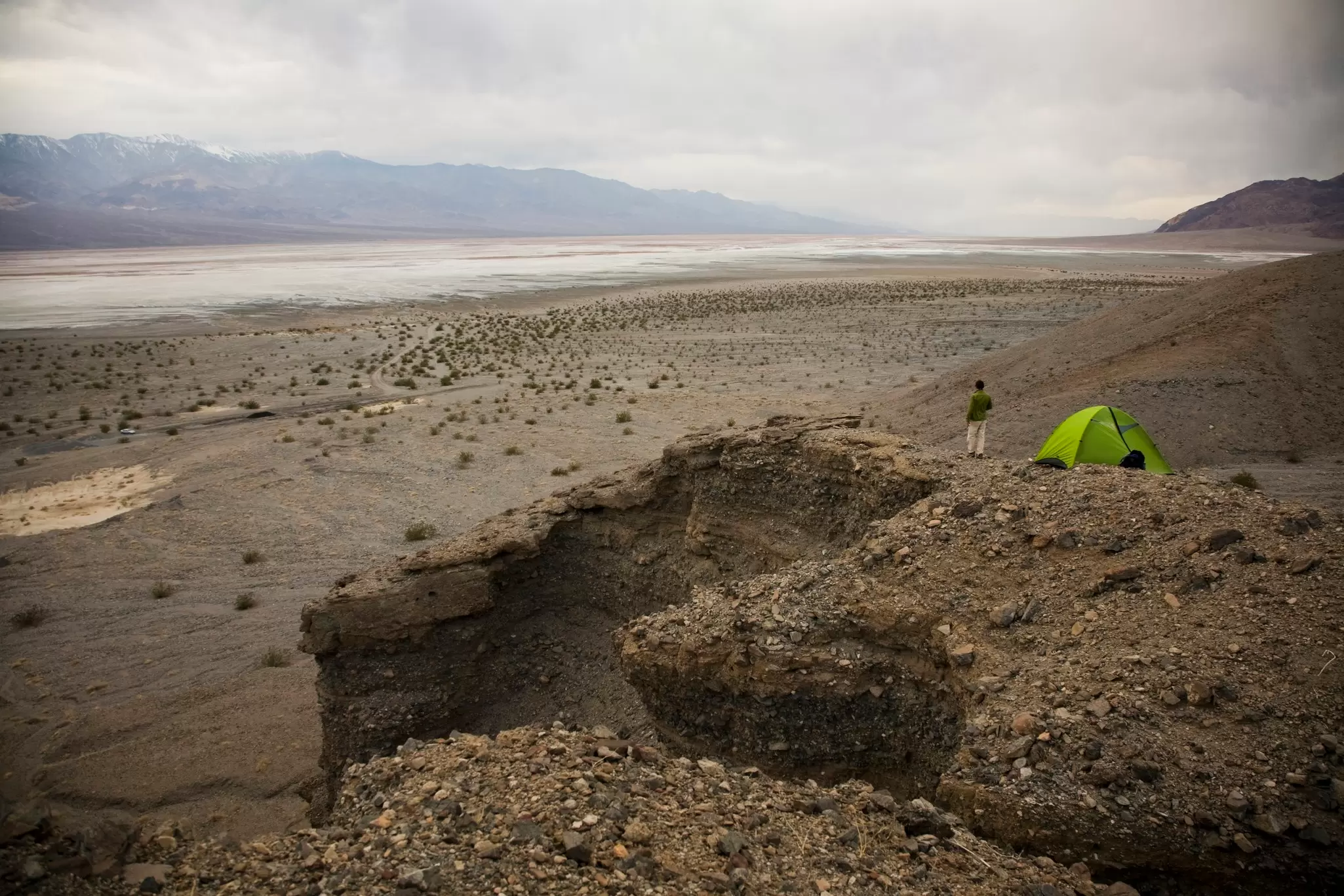 A man stands near his green tent overlooking Death Valley National Park,CA.