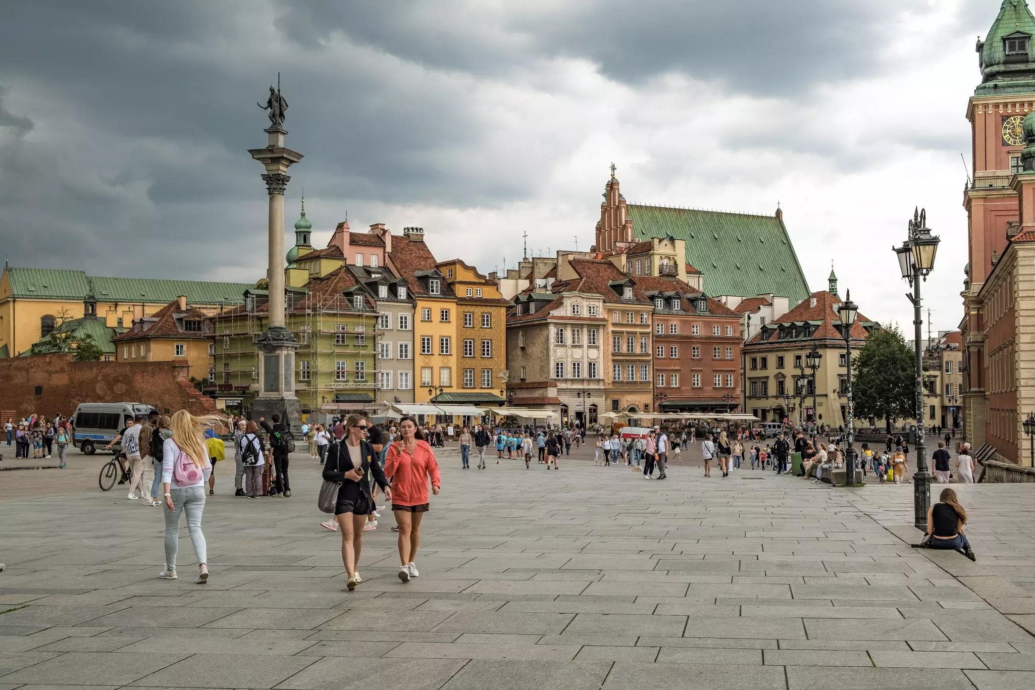 People walking in Castle Square with colorful townhouses and Sigismund's Column in the Old Town district