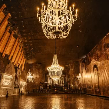 An underground chapel carved from rock salt, with chandeliers above a polished salt floor and carved reliefs.