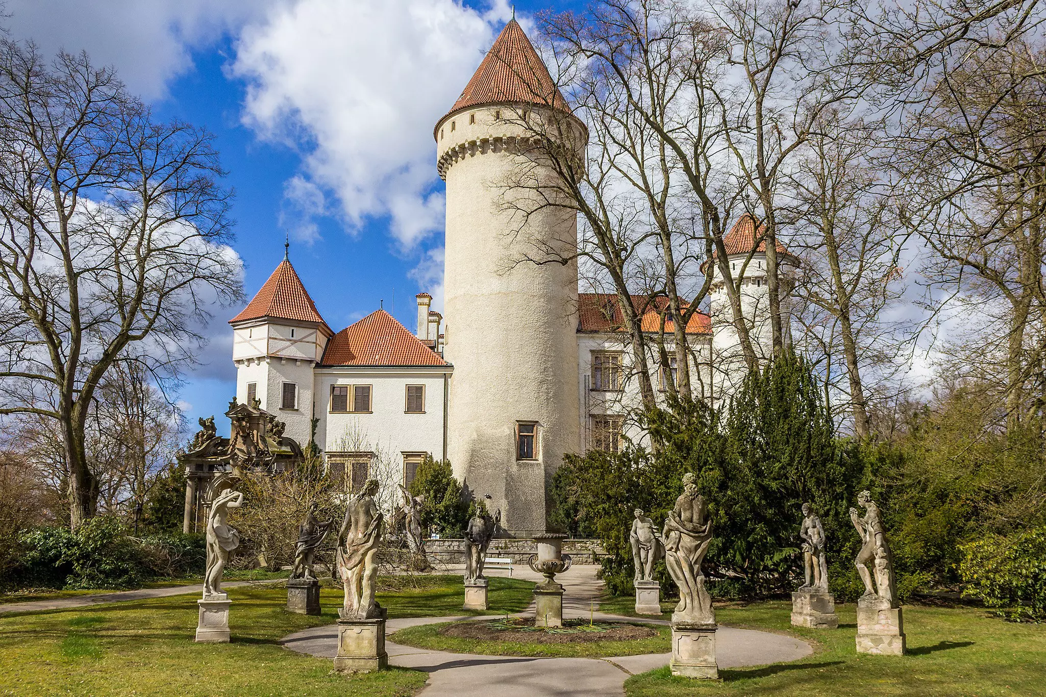 Statues around a landscaped walkway leading to a castle.