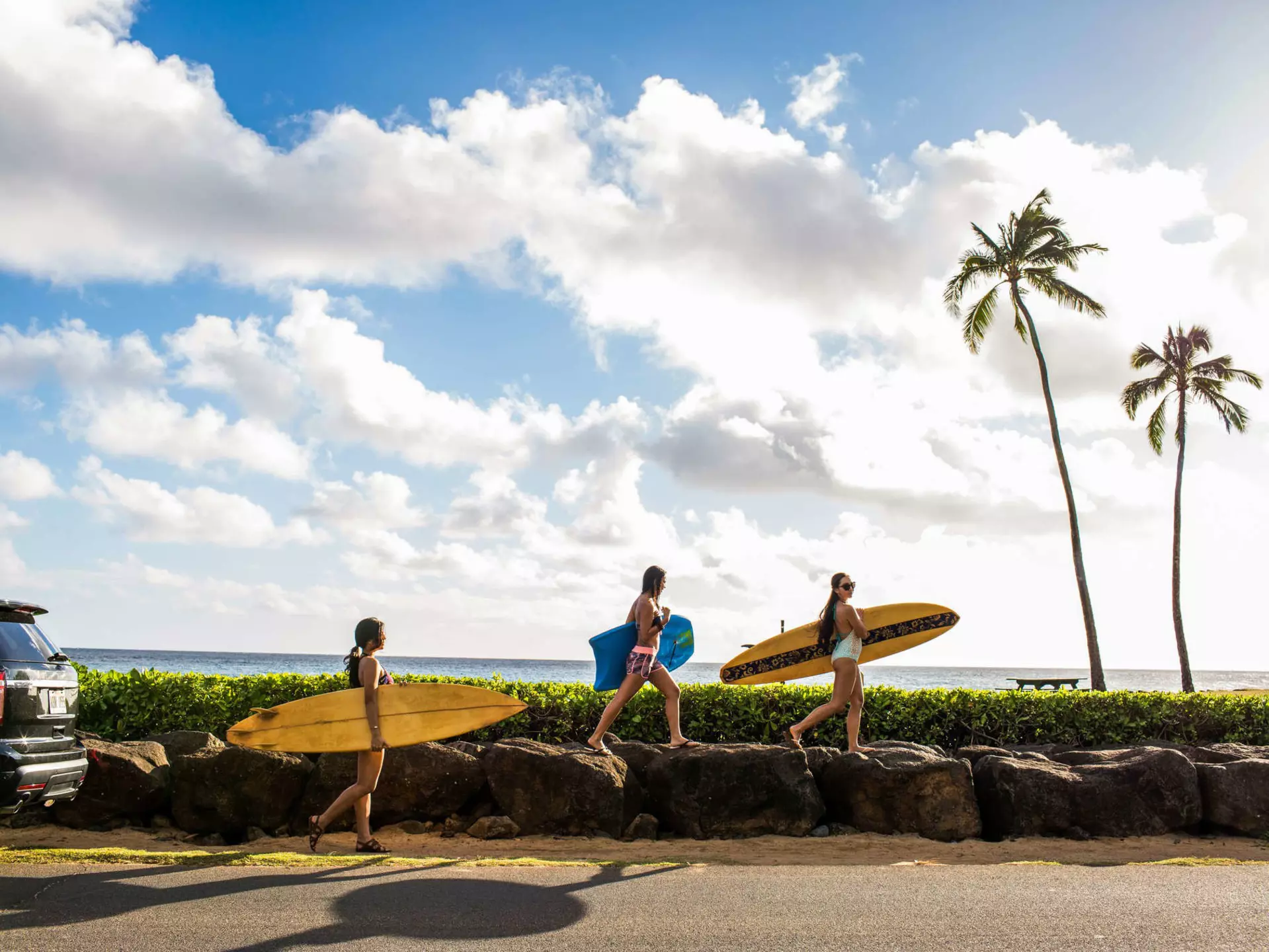 Pacific Islander surfers carry their boards to the water.