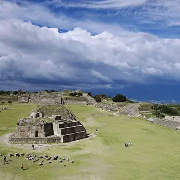 People visit an ancient pyramid and other structures in an archaeological site