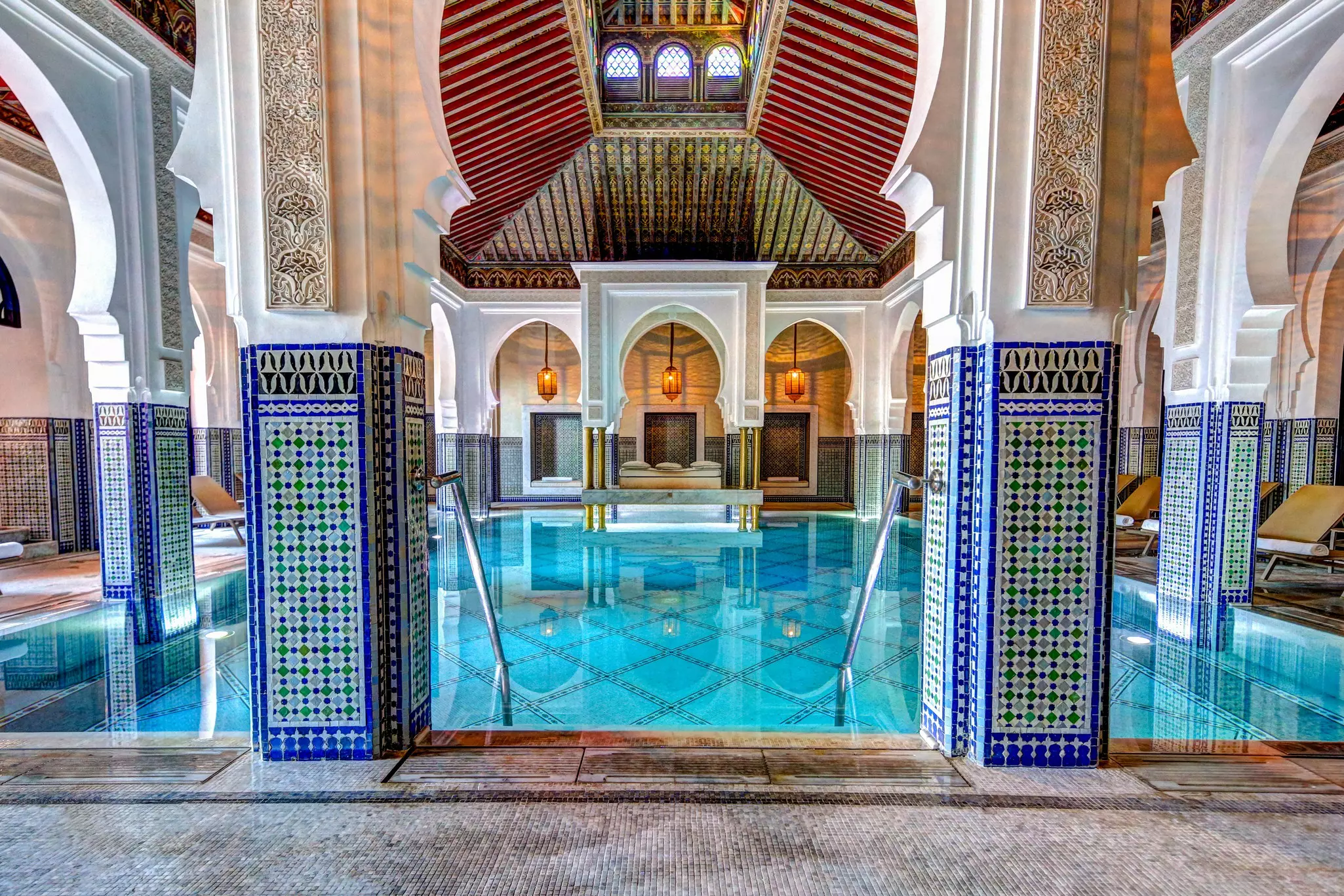 a blue pool with red roof and bight blue tiles surrounding