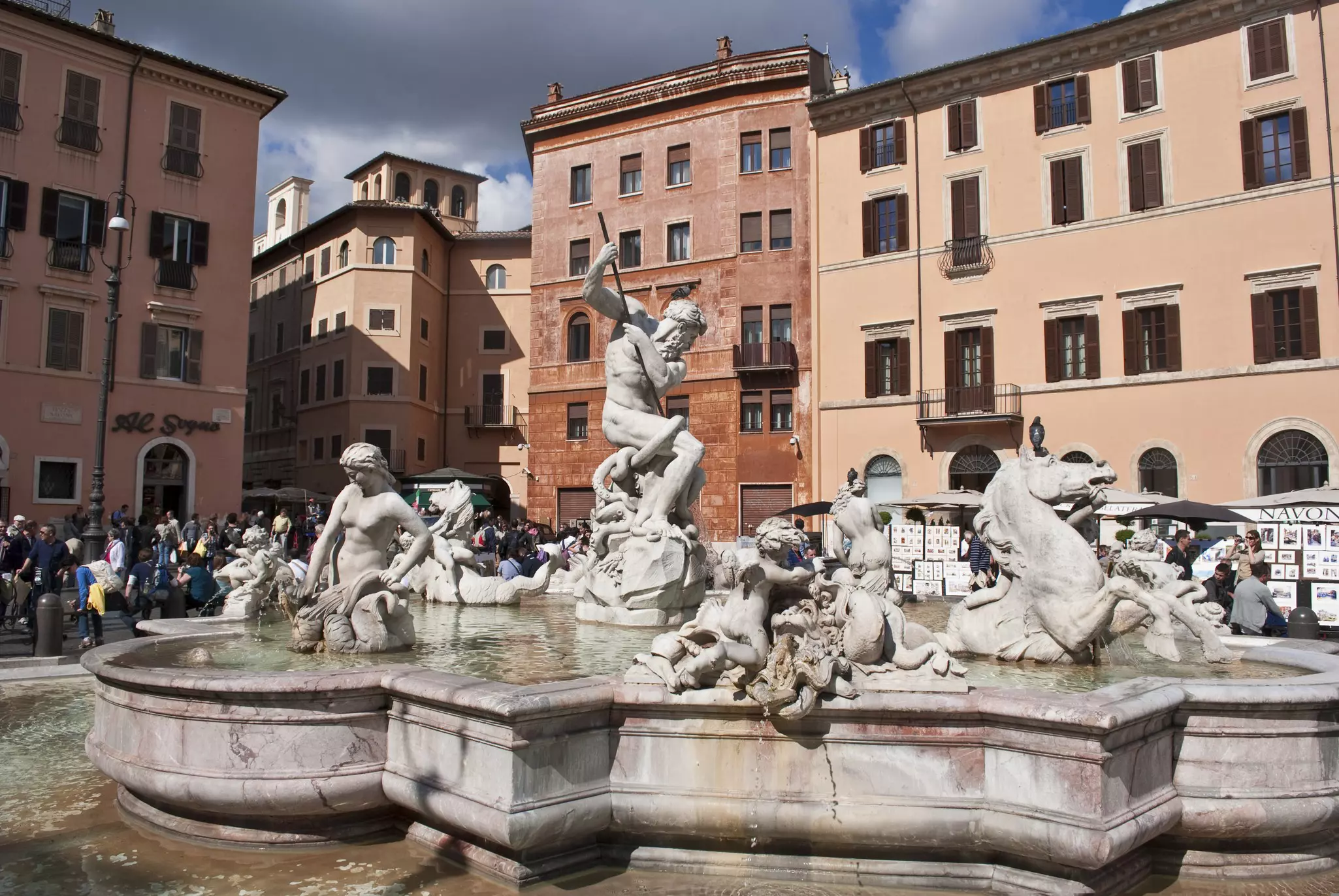 Terracotta-colored buildings surround the Fontana del Nettuno in Piazza Navona in Rome, Italy.