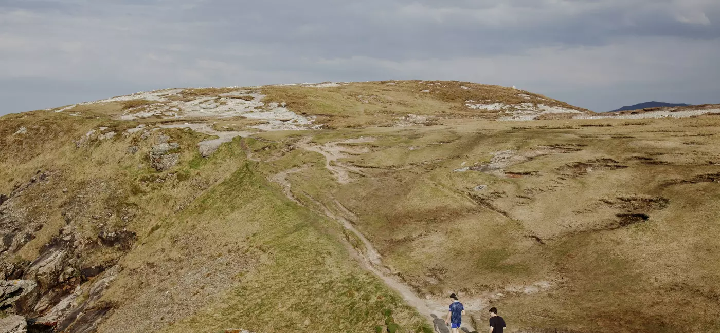 Two lads in shorts and t-shirts follow a hiking path uphill