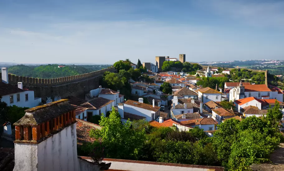 Óbidos, Portugal: whitewashed houses with terracotta roofs inside crenellated walls, the castle towers on the hilltop