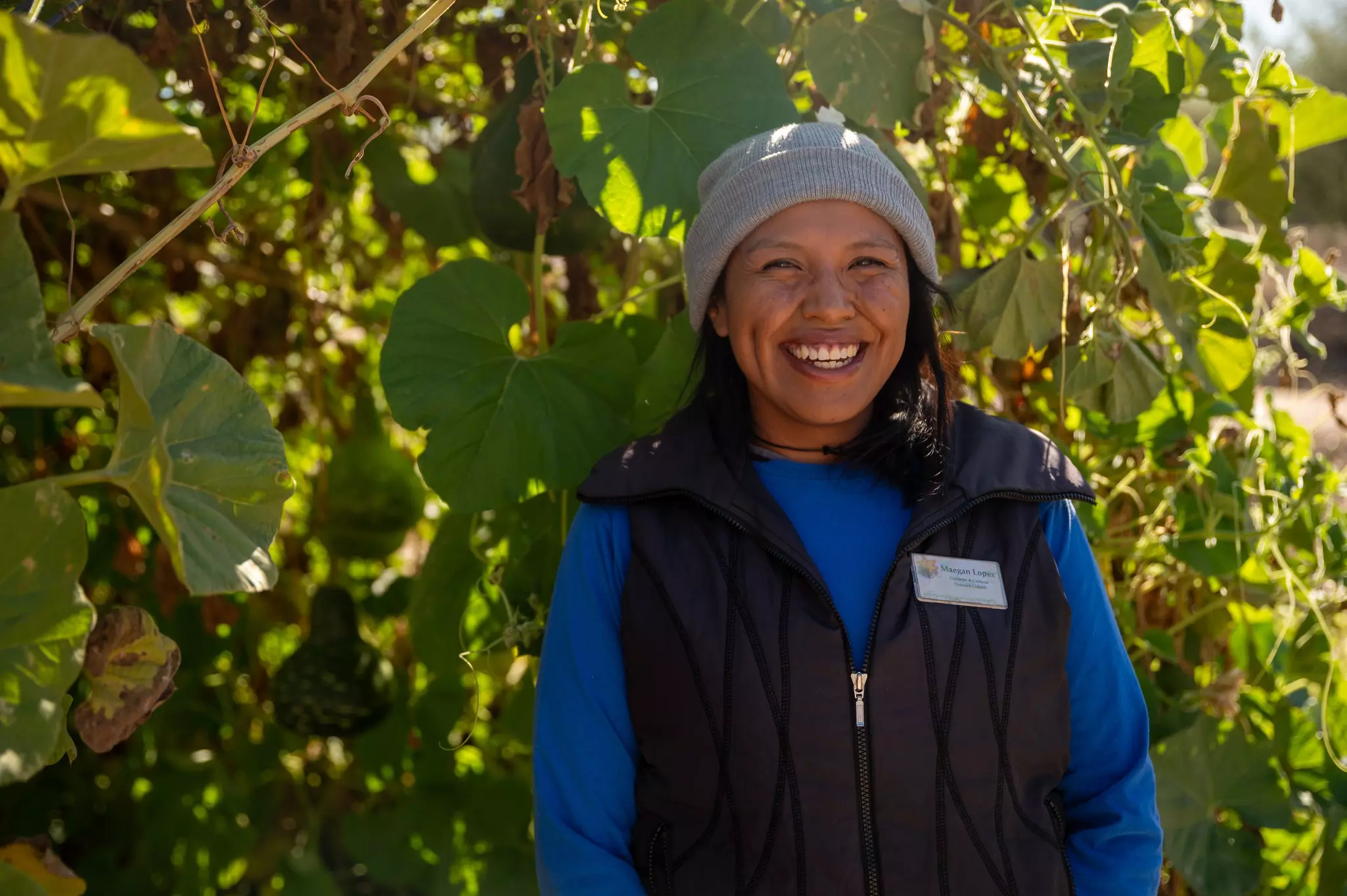 A woman stands in front of a bus and smiles at the camera