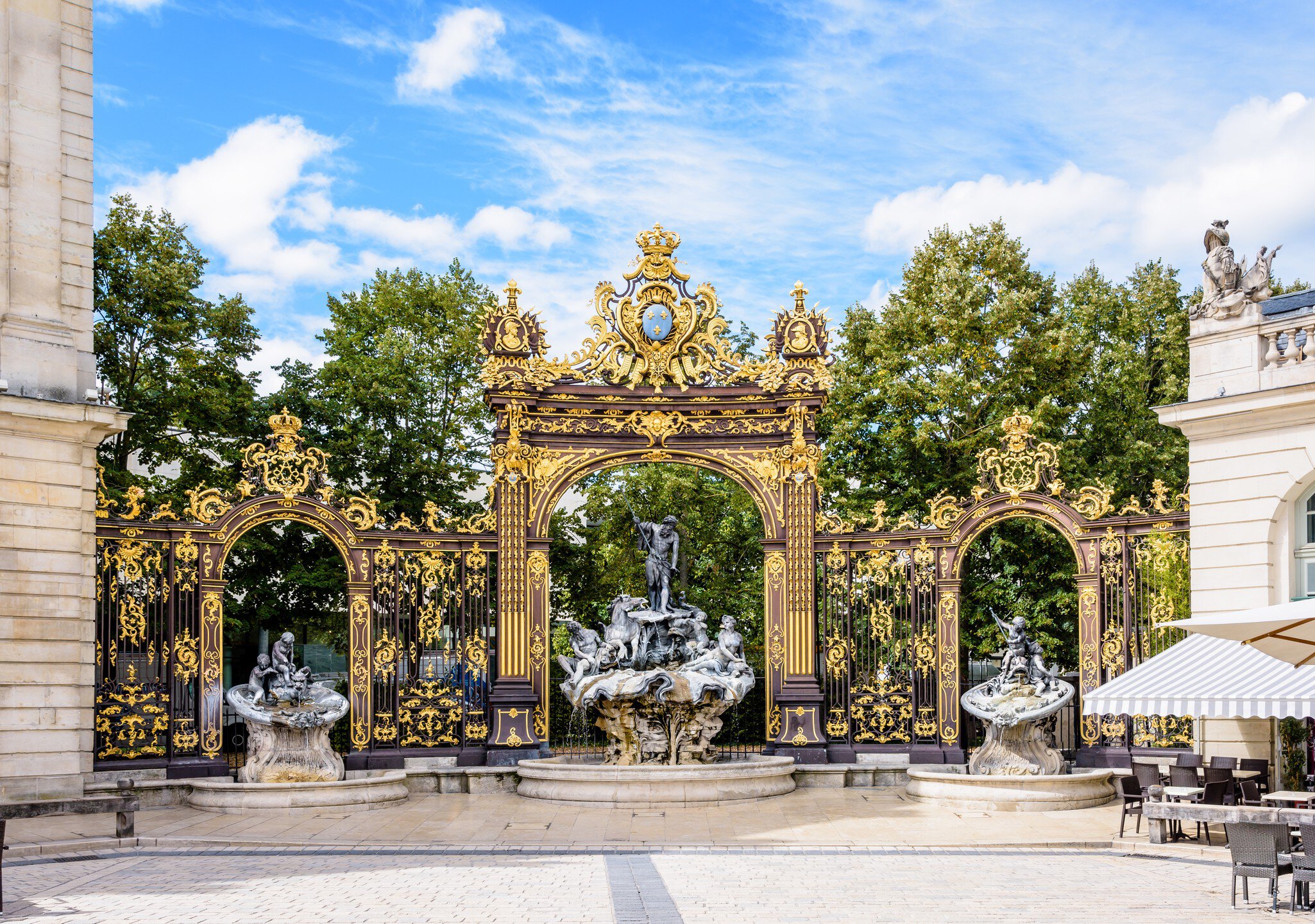 The fountain of Neptune in the Rococo style and the gilded wrought iron portico in the north-west corner of the place Stanislas in Nancy, France.