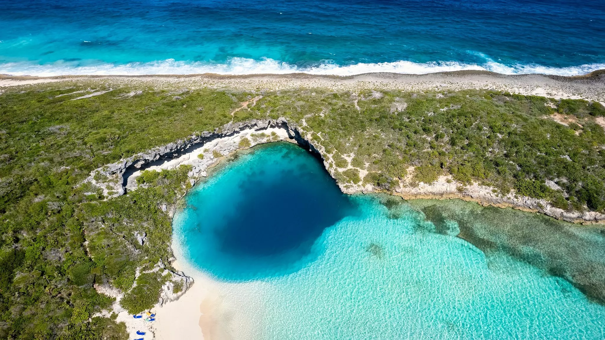 Aerial top view of the famous Dean's blue hole with the connecting turquoise lagoon next to the blue ocean, Long Island, Bahamas.