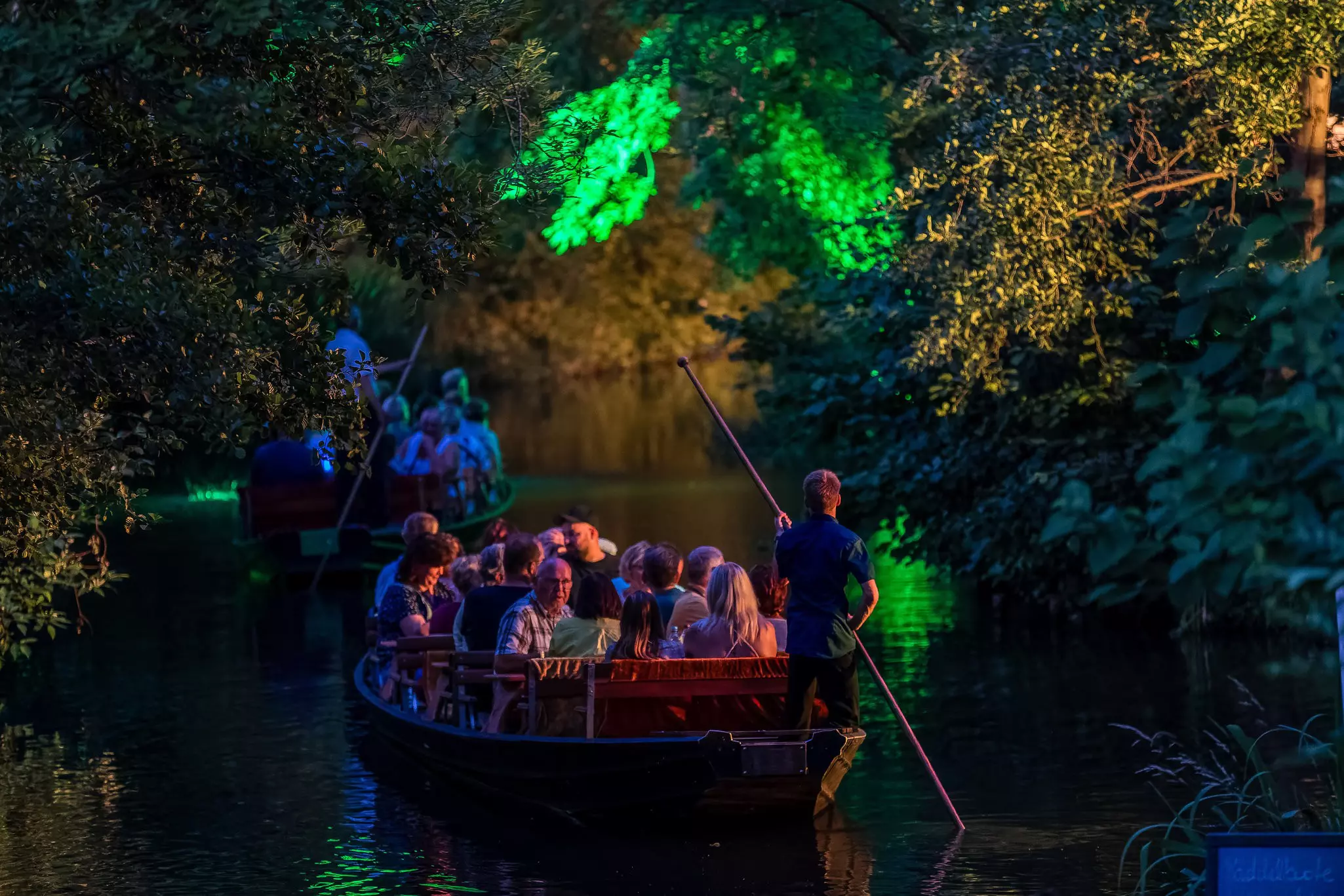 Two boats full of people on a night cruise on a river
