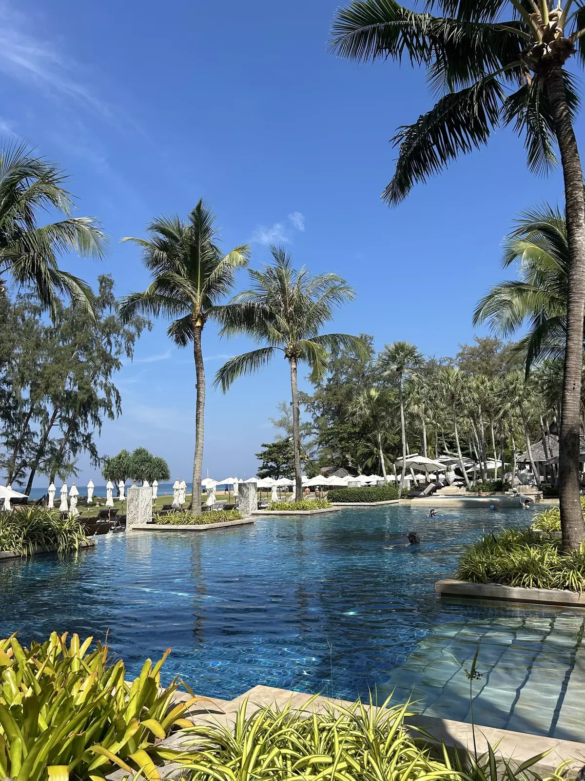 Sun loungers and umbrellas surround a large pool at a resort.
