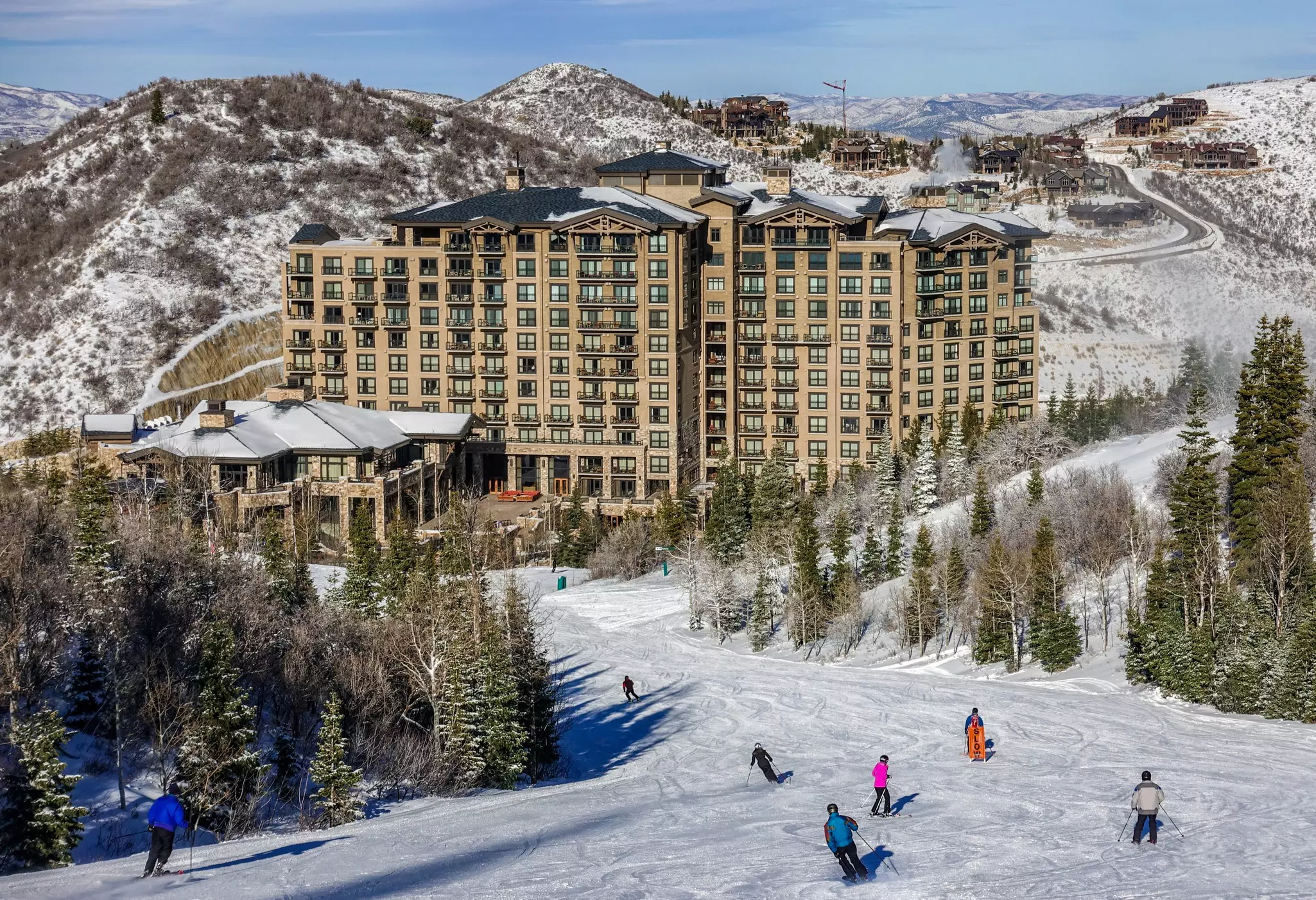 Skiers ski down the snow covered slopes in front of the lodge on a sunny winter day at the Deer Valley Ski Resort, which is close to Park City and The Canyons, a short drive from Salt Lake City, Utah.