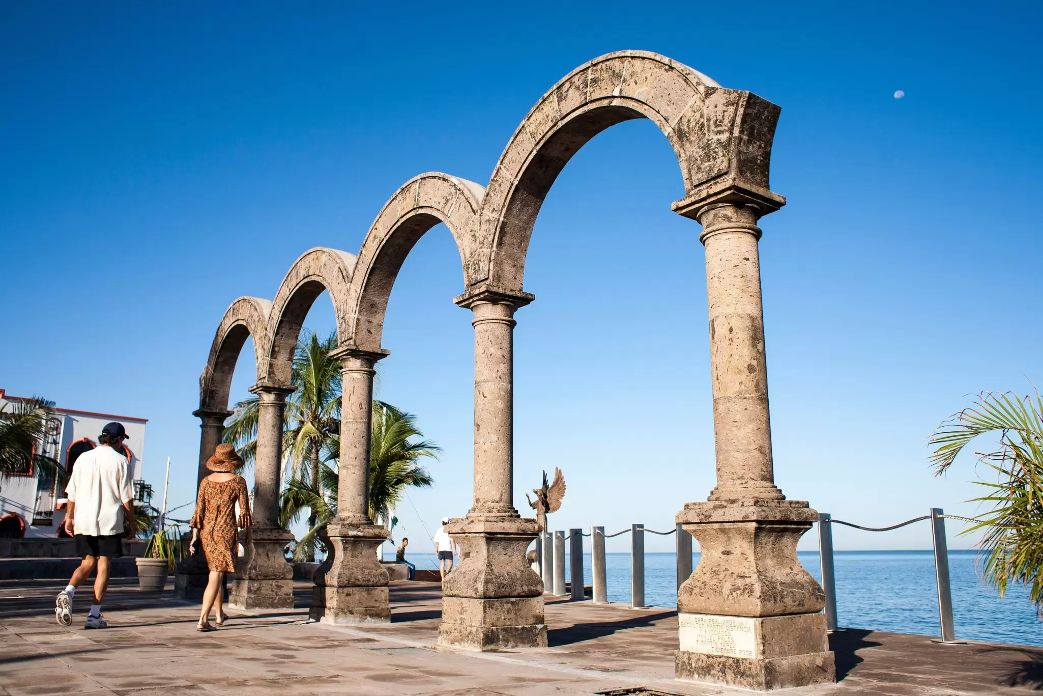 People walking by Los Arcos on the sea promenade in Puerto Vallarta, Mexico.