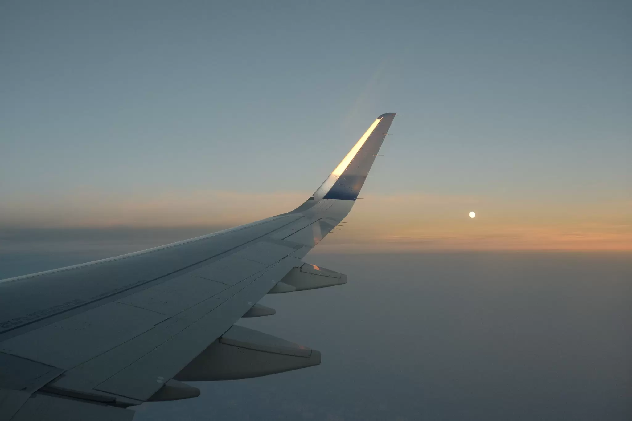 view out of a plane window of the plane's right wing and the sunset