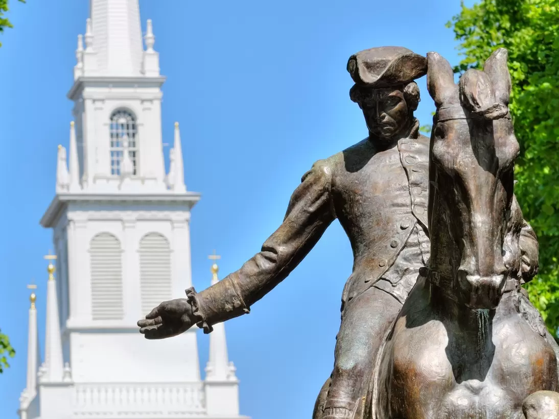 A statue of a man on horseback with a white church steeple in the background.
