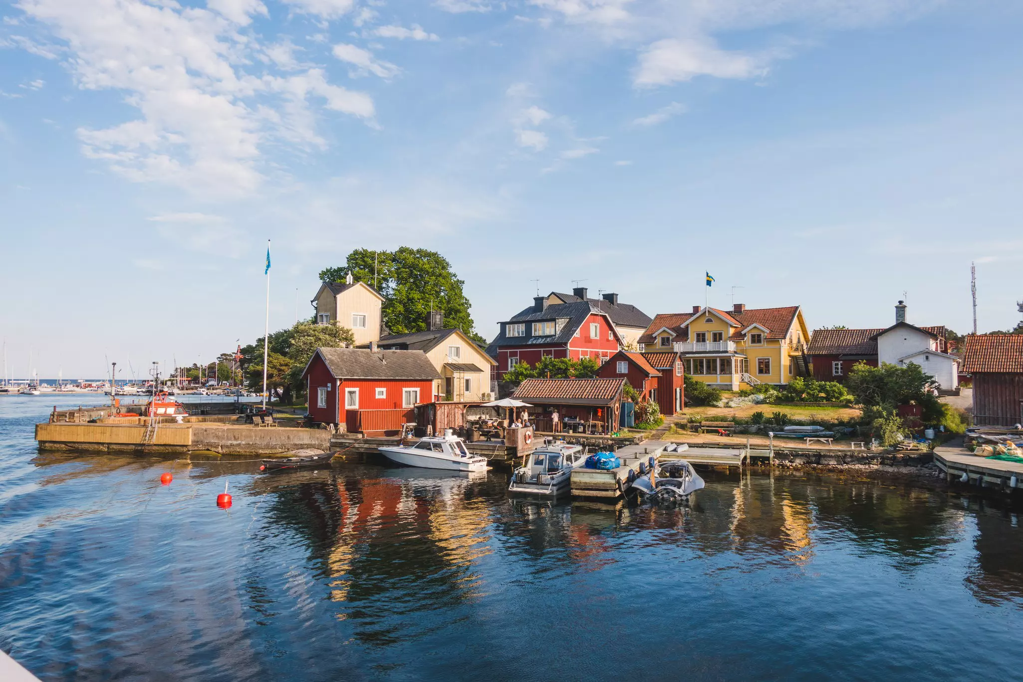 Small wooden chalets and a dock at the edge of the water on an island bathed in sunshine