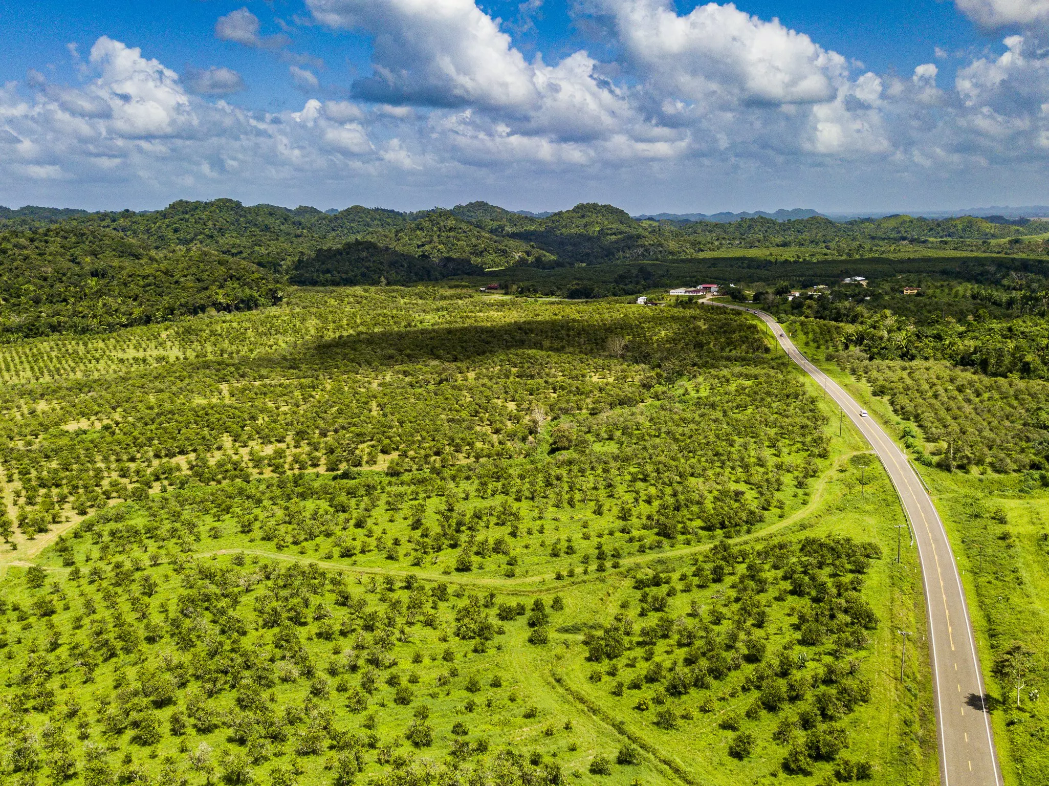 A highway snakes through a gently rolling landscape of green hills and fields.