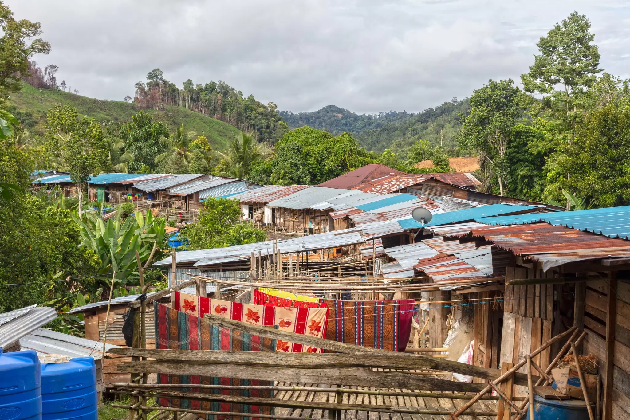 A long row of wooden homes with corrugated roofs forming an Iban longhouse in Batang Ai National Park. 