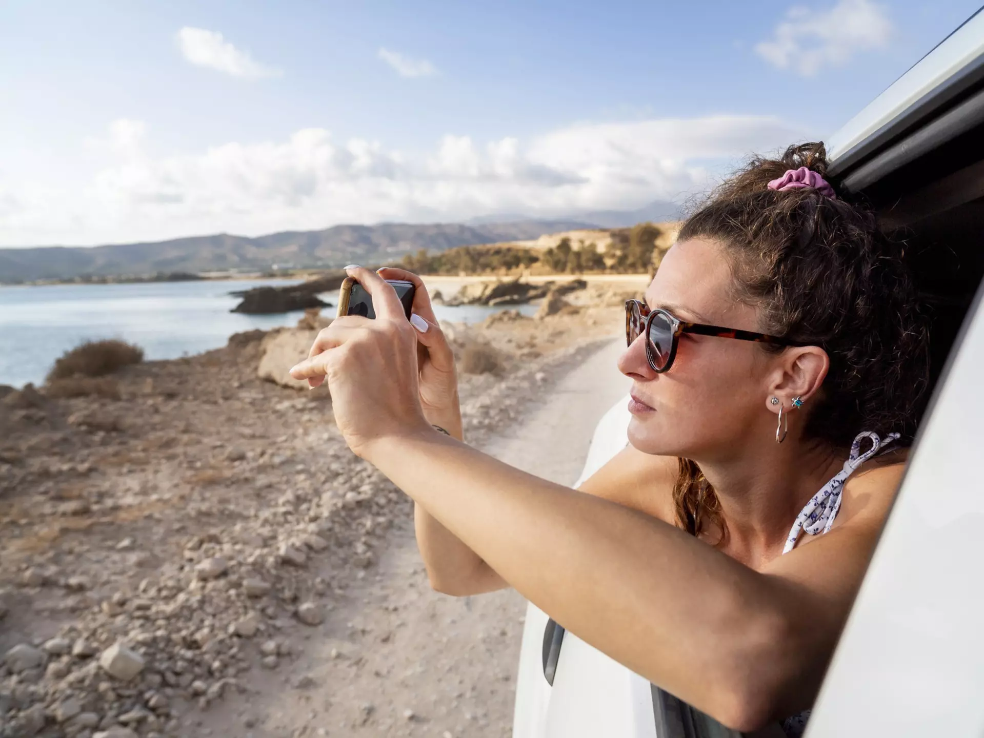 A woman taking a photo through a car window near Balos Beach, Crete