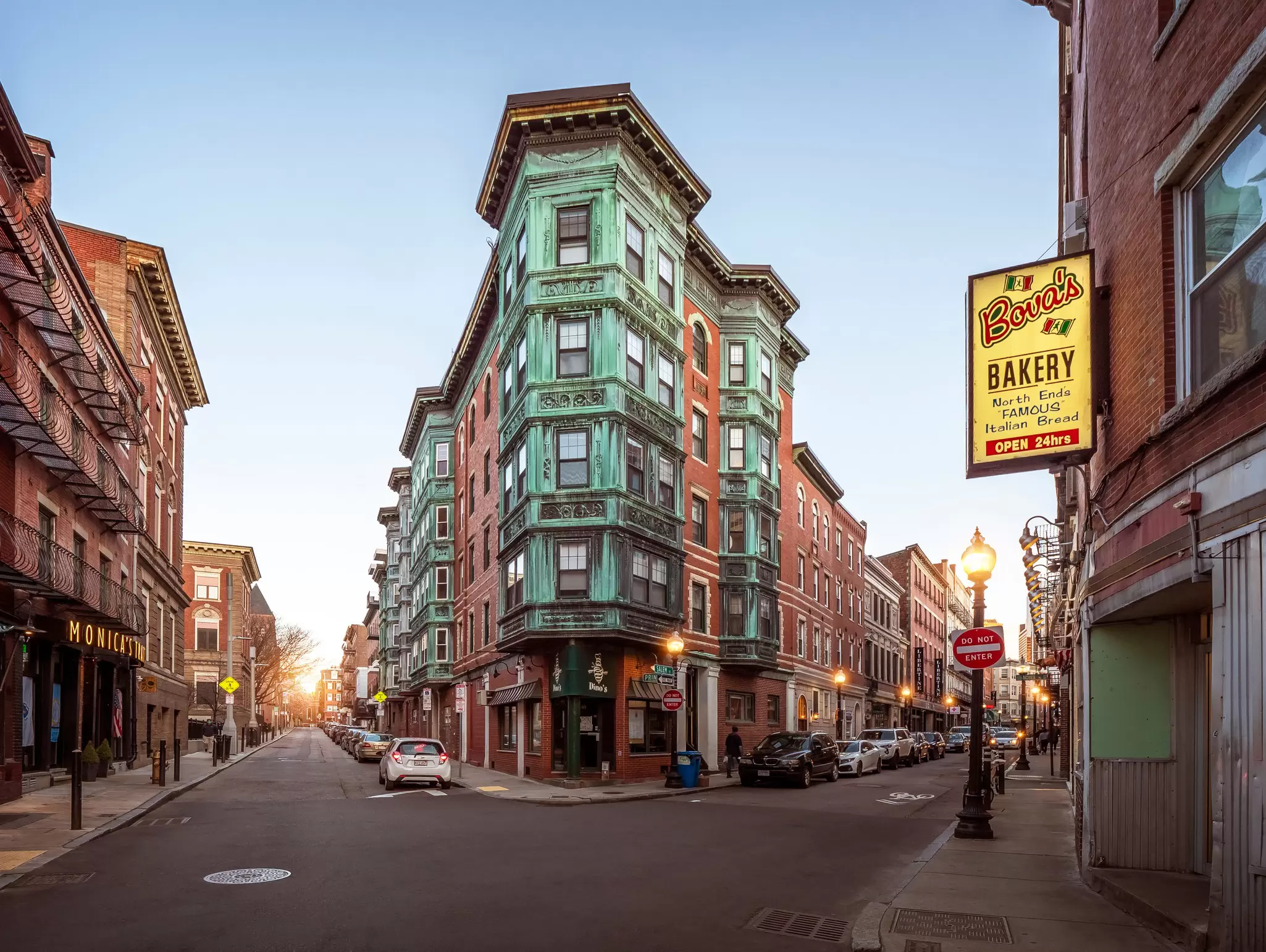 A charming five-storey heritage building painted green on a street corner in Little Italy, Boston