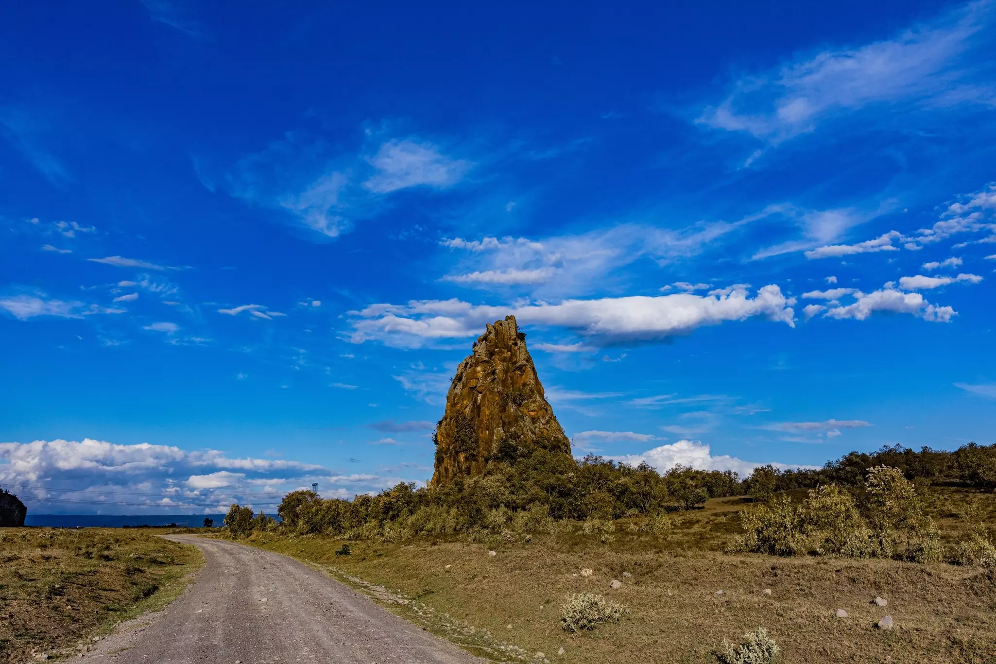 A large rock formation on the side of a gravelly road