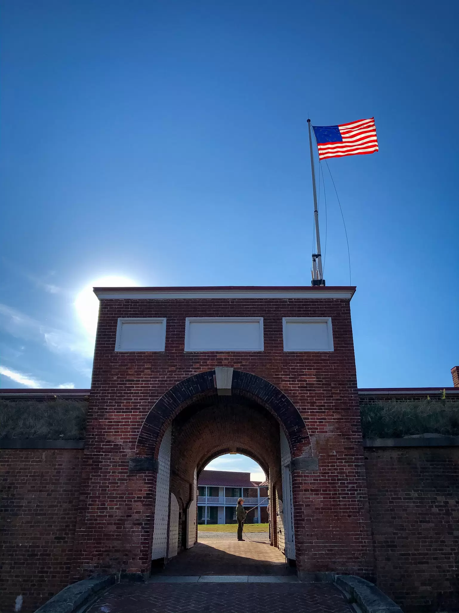 A view into the brick arched gate to Fort McHenry, Baltimore, Maryland. The US flag flies above the fort entry.
